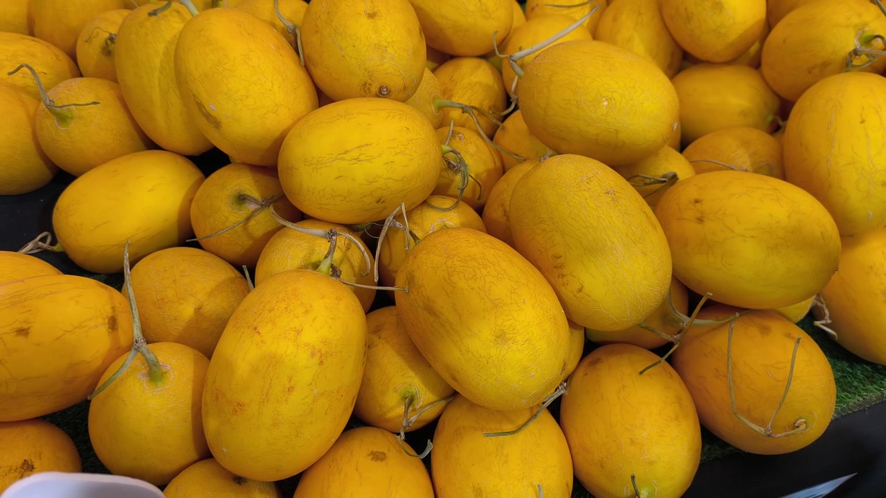 Meloni canarini freschi sono impilati ordinatamente su un tavolo per l'esposizione. Questi frutti giallo brillante sono pronti per la vendita in un mercato locale.