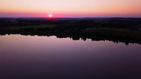 colorful sunset over a peaceful lake, sarrounded by trees