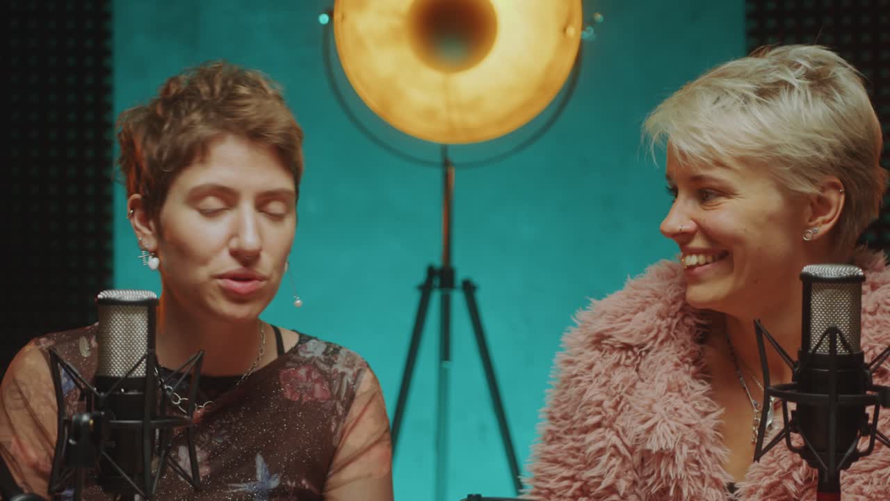 Two Young Female Bloggers Giving Interview in Podcast Recording Studio