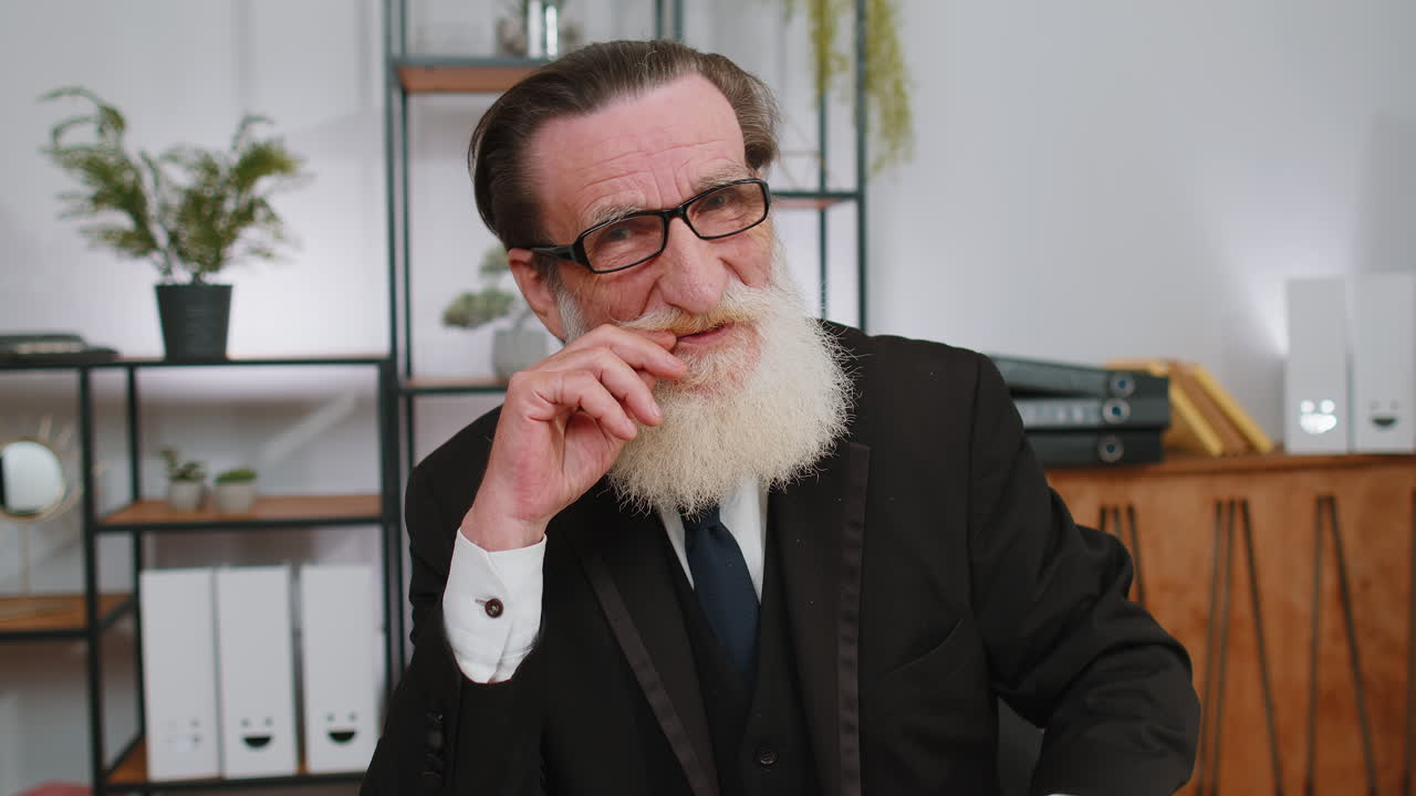 hombre de negocios sénior feliz y confiado con gafas mirando a la cámara con una sonrisa en el lugar de trabajo de la oficina en casa