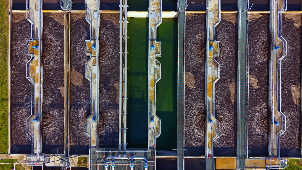 Water treatment facility shows multiple tanks with flowing water during daylight hours in a city setting