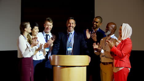 happy multi-ethnic business people applauding mature businessman on stage in seminar 4k