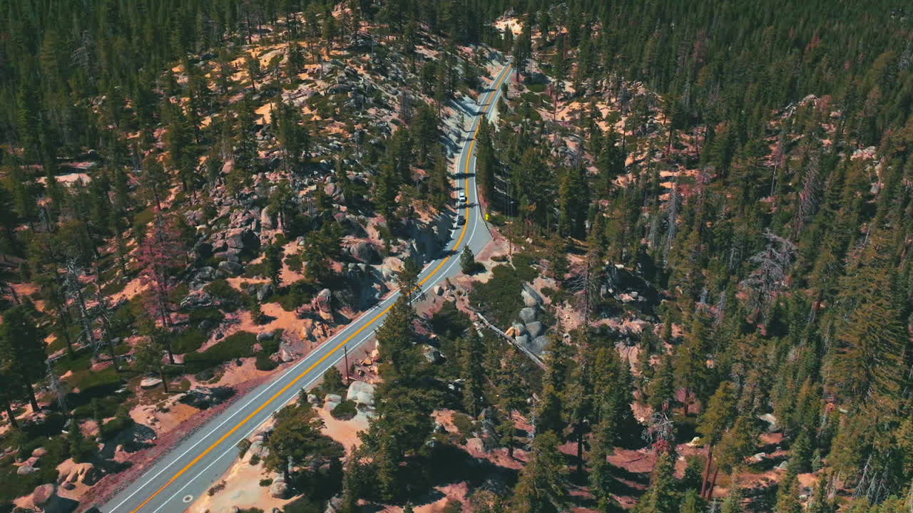 Mountainous wooded territory with road going along it. Pine tree forest growing on rocks. Top view.
