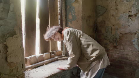 chica pelirroja tratando de escapar por la ventana de un edificio en ruinas durante una grabación
