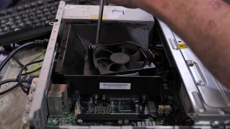 técnico informático desenroscando el ventilador de la fuente de alimentación de la pc con un destornillador, cerrar