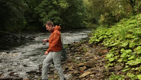 hand-held tracking shot of a fisherman casting and reeling in his lure