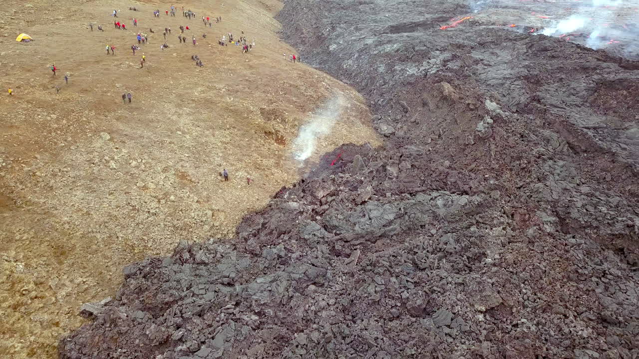 toma de drones de lava enfriándose con gente cerca observando el volcán.