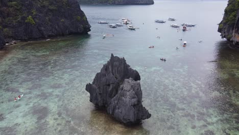 Aerial-View-of-Tourists-Enjoying-Kayaking-in-Cadlao-Lagoon's-Emerald-Waters,-El-Nido