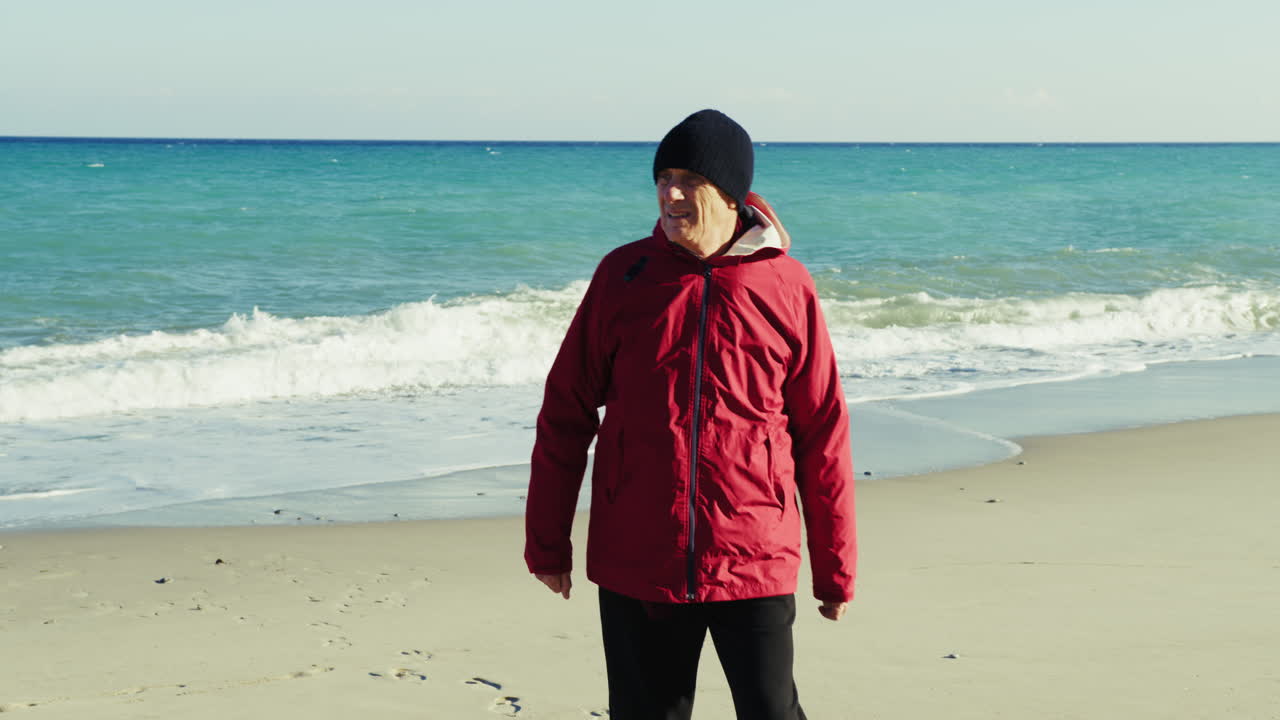 Man in a Jacket Waves to People by the Sea