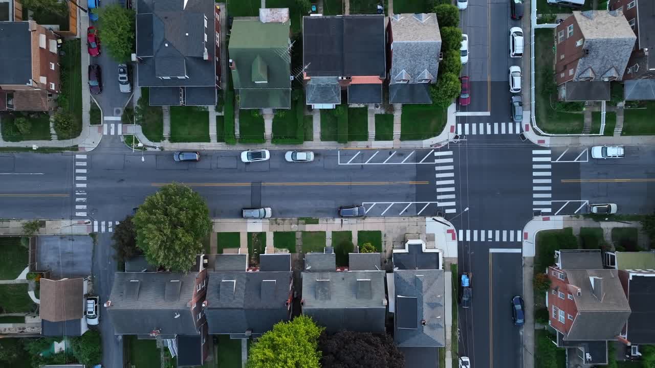 Intersection with crosswalks, cars, and surrounding houses in urban America
