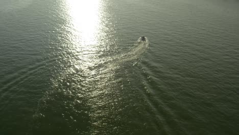 surrounded by water and the light of the setting sun, a motorboat roams