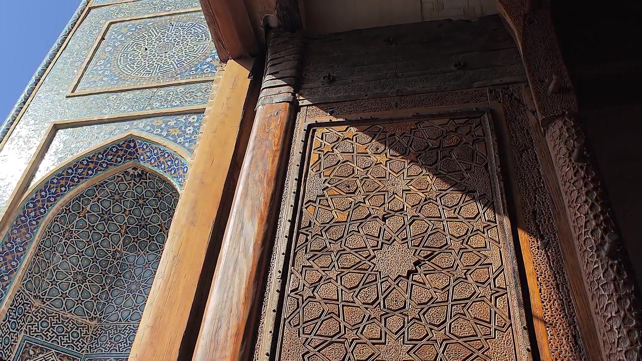 Intagli in legno intricati e piastrellatura blu all'ingresso di una moschea storica