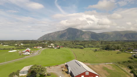 aerial shot flying over a farm surrounded by mountains and fields in norway