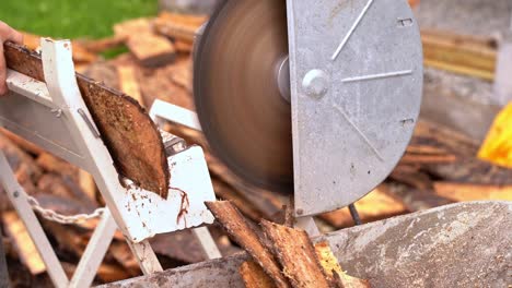 man using crosscut saw to cut firewood from wooden pine planks - closeup of saw and wood falling into wheelbarrow in 20 percent slow motion and blurred background