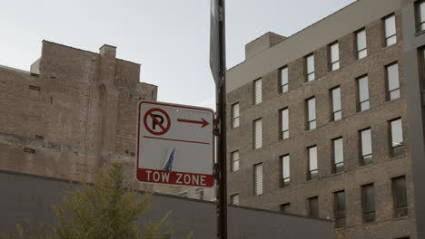 No-Parking-and-Tow-Zone-sign-posted-on-city-street-with-buildings-in-background