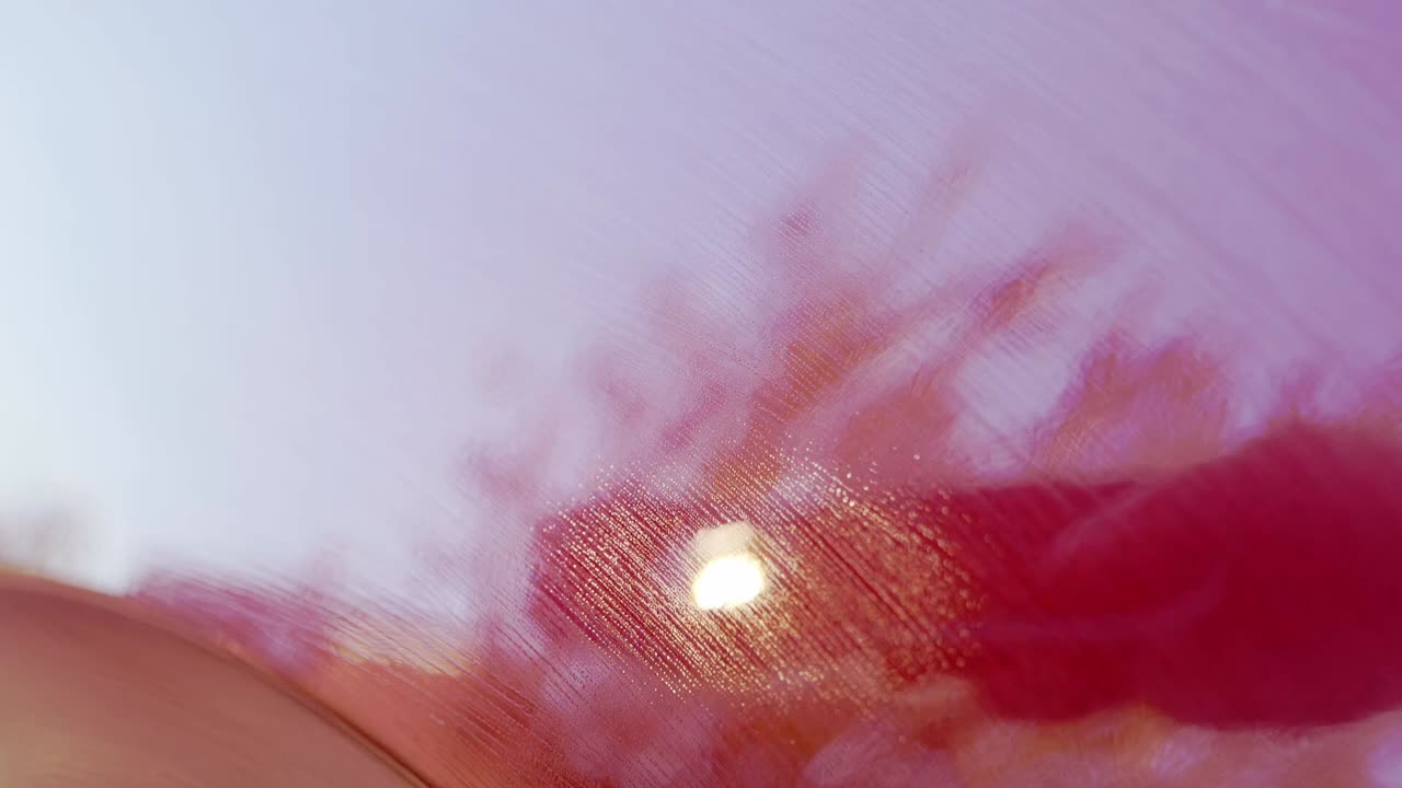 Inspecting freshly applied ceramic coating applied to cherry red car outdoors with LED torch