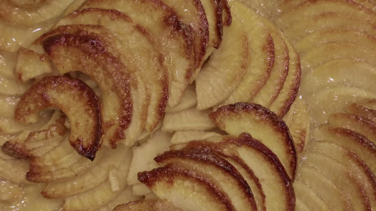 primer plano de una tarta de manzana caramelizada que muestra rodajas de fruta doradas al horno en un glaseado dulce