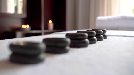 detail of hot stones on a massage table with candle in background