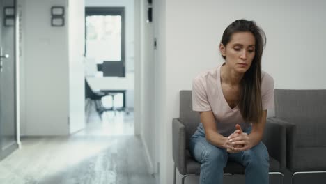 Wide-shot-of-stressed-caucasian-woman-sitting-in-clinic-waiting-room-and-squeezing-a-stress-ball.