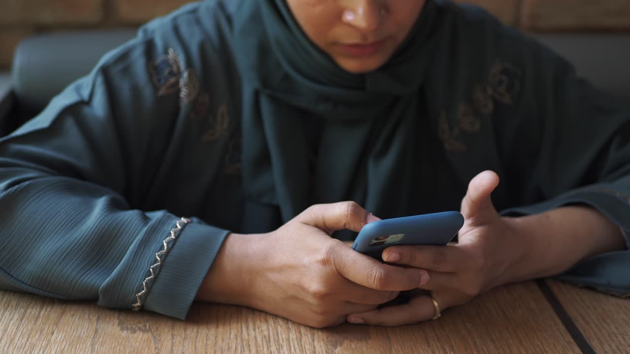 히자브 를 입은 여자 가 드폰 을 보고 있다