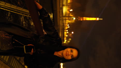 Vertical-video-of-a-beautiful-young-woman-on-a-boat-on-the-Seine-river-in-Paris,-with-the-Tour-Eiffel-in-the-background,-at-night,-France