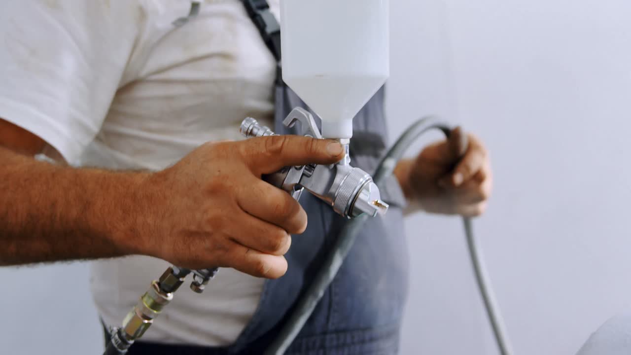 Mannlig mekaniker bruker spraymaling i garasje 4k