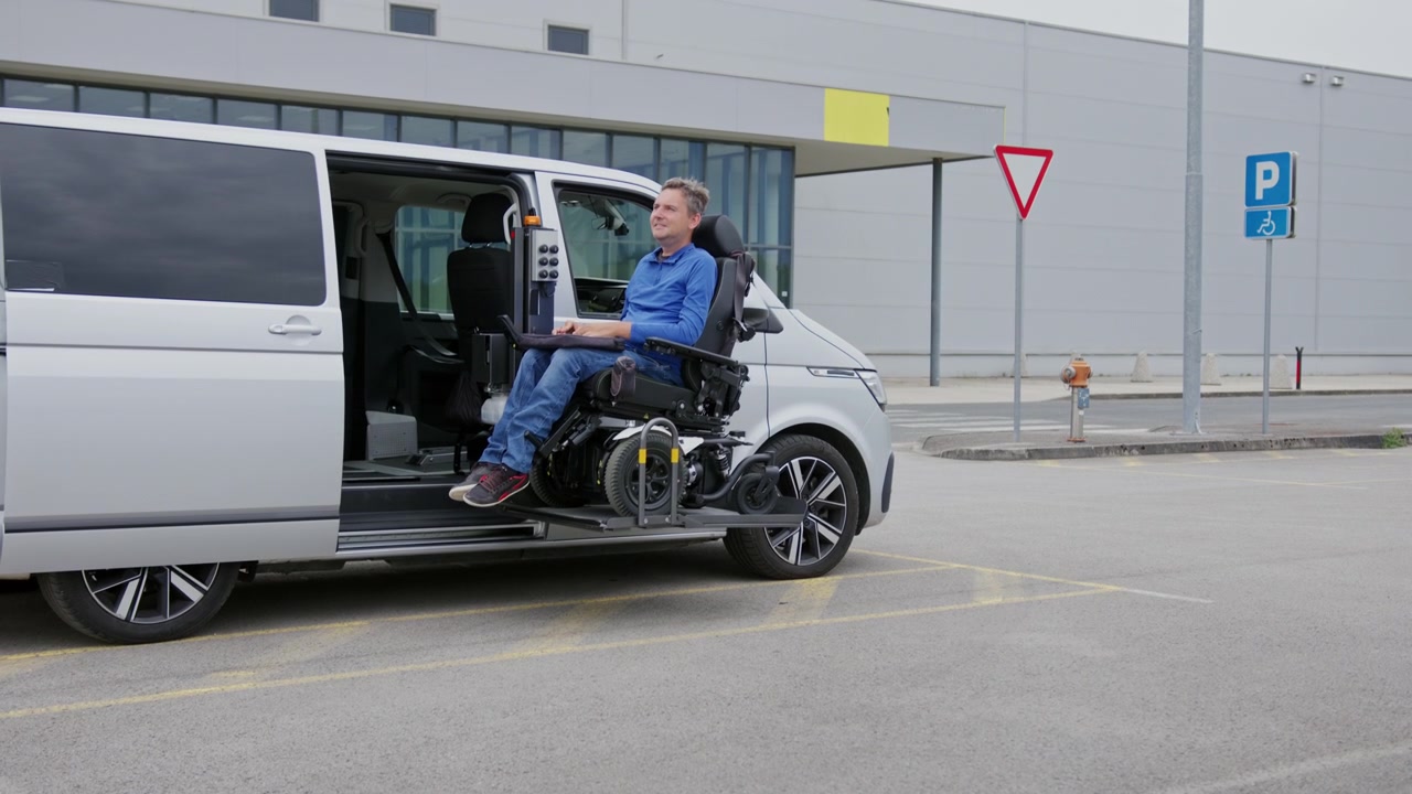 Utente in sedia a rotelle che sale su un furgone adattato tramite una piattaforma elevatrice, ingresso accessibile per persone con