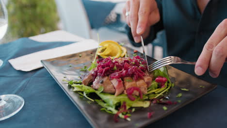 details of man hands cutting the slices of the tuna gourmet dish at the resort