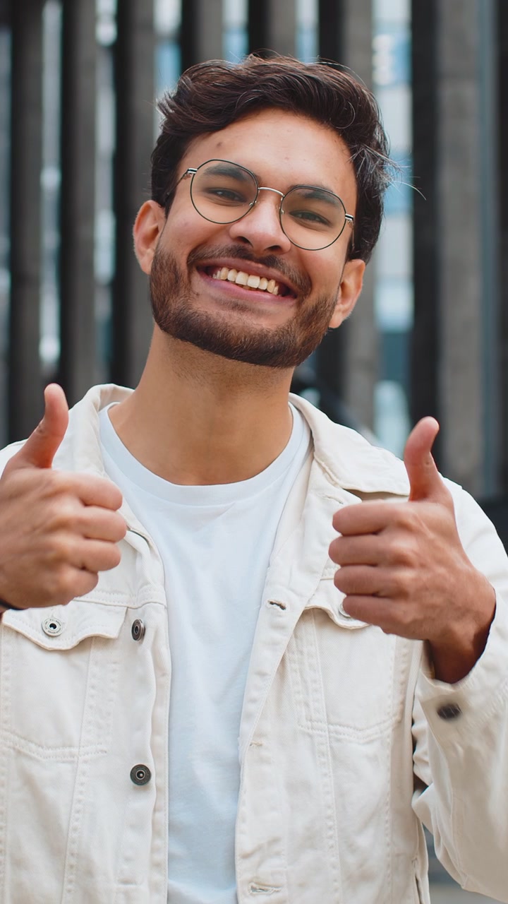 Hombre indio feliz mostrando el pulgar hacia arriba, señal de algo positivo, en una calle de la ciudad.