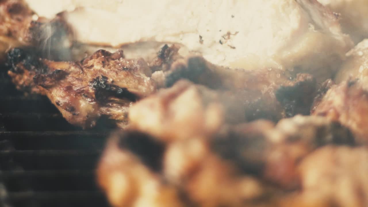 숯불 그릴에서 나오는 닭 날개와 연기의 슬로우 모션 클로즈업 샷