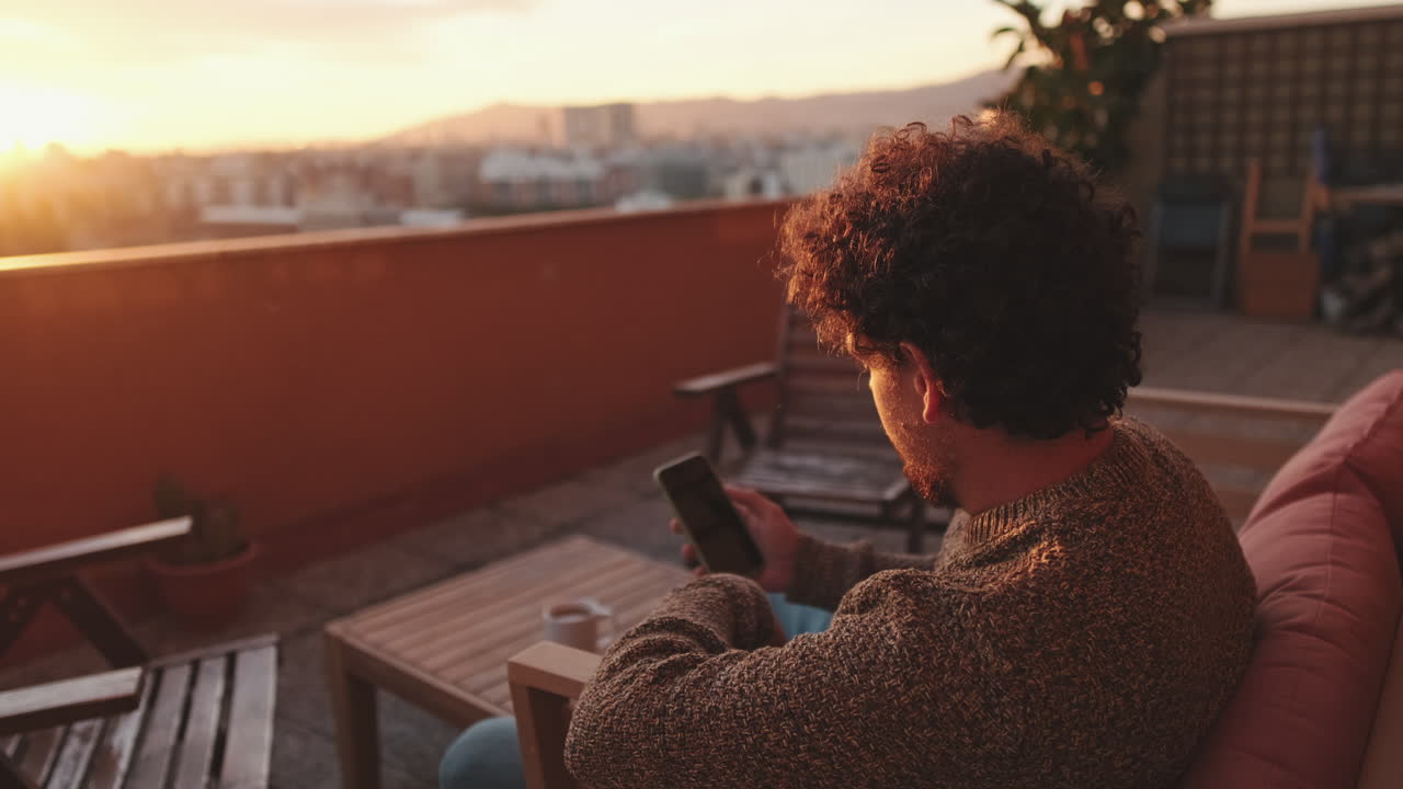 Hombre en la azotea al atardecer usando el teléfono