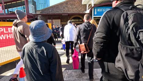 pedestrians crossing road towards market entrance