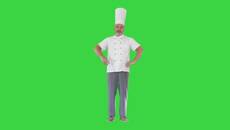 cocinero serio con los brazos cruzados mirando a la cámara en una pantalla verde, llave de croma