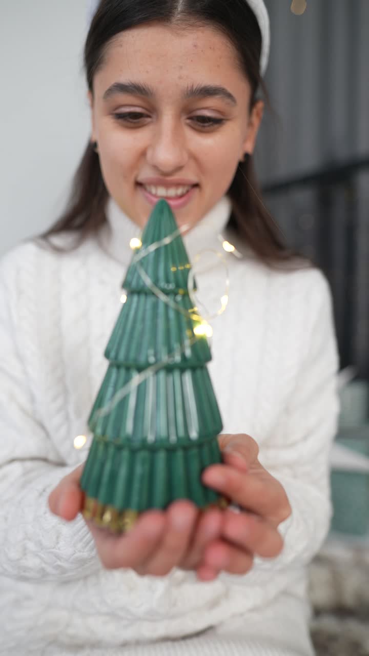 mujer joven sosteniendo un ornamento de árbol de navidad
