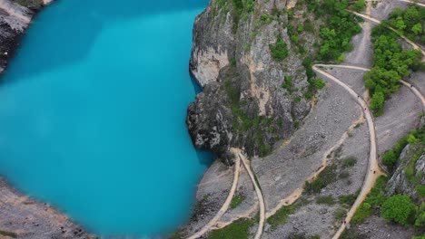 Aerial-view-of-blue-water-lake-formed-in-deep-sinkhole-surrounded-by-tall-cliffs-in-Imotski,-Croatia