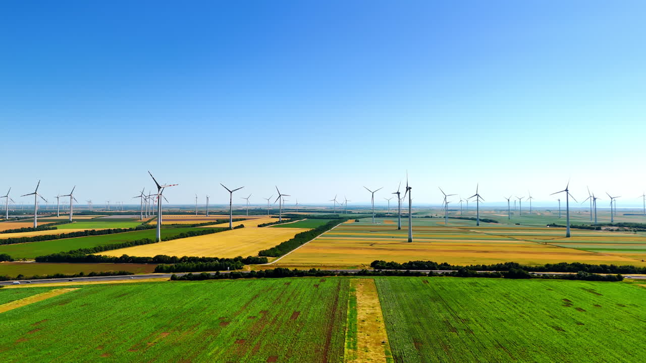 Yellow and green fields with numerous wind mills. Countryside landscape used for wind farms. Aerial view