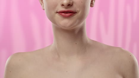 close-up of a young woman's lips and neck against a pink background