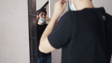 man in front of the wardrobe put on a mask at home