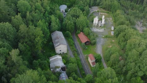 aerial view of abandoned industrial buildings and train tracks in a forest
