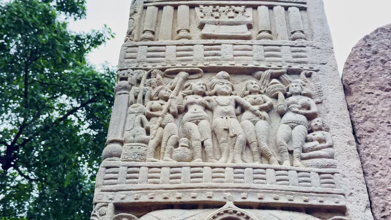 As the camera tilts up, the Torana of Sanchi reveals intricate carvings of figures and motifs, showcasing the storytelling artistry of ancient Buddhist architecture and cultural heritage