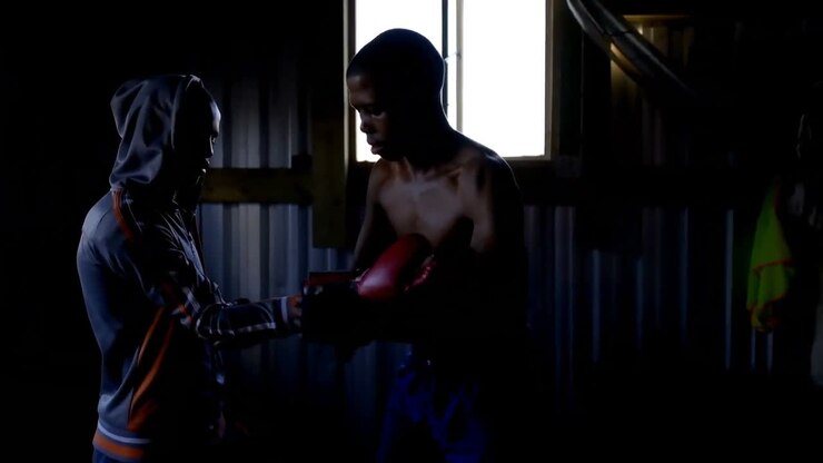 Allenatore che assiste un pugile uomo nell'indossare i guantoni da boxe 4k