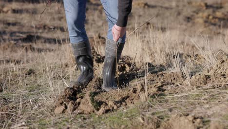 un homme en bottes compacte le sol avec ses pieds - de près