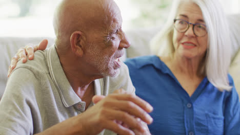 Senior-caucasian-woman-consoling-sad-diverse-senior-male-friend-in-living-room,-slow-motion