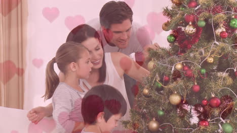 animación de la familia decorando el árbol de navidad contra el corazón rosa