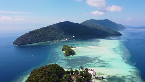 rising aerial of remote tropical islands surrounded by coral reef in popular diving destination of raja ampat in west papua, indonesia