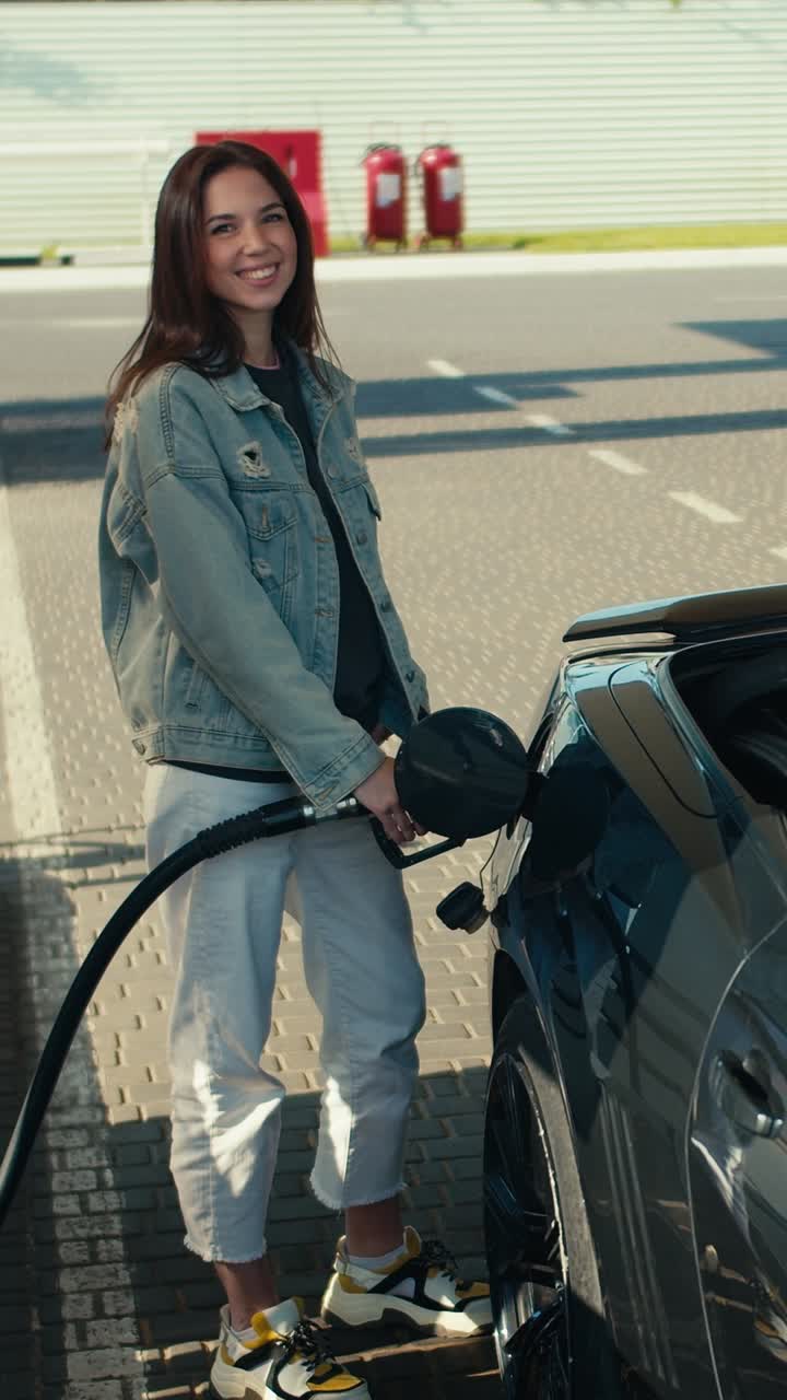 Donna che fa rifornimento all'auto alla stazione di servizio