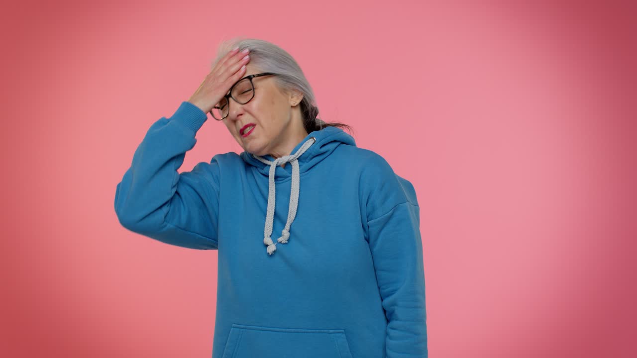 Upset senior granny woman making face palm gesture, feeling bored, disappointed in result, bad news