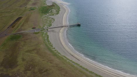 Paso-Aéreo-Sobre-La-Playa-De-Onundarfjordur-Con-Embarcadero-Y-Agua-Azul-En-Islandia---Inclinación-Hacia-Abajo