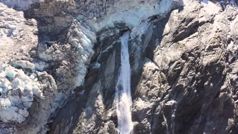 Vista-Aérea-De-Una-Cascada-Con-Agua-Derretida-De-Un-Glaciar-Moribundo-En-Suiza