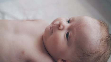 cute infant boy with bright blue eyes lies on changing table